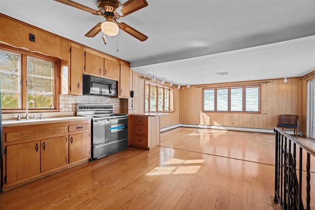 kitchen with black microwave, stainless steel range with electric cooktop, light countertops, a wealth of natural light, and light wood finished floors