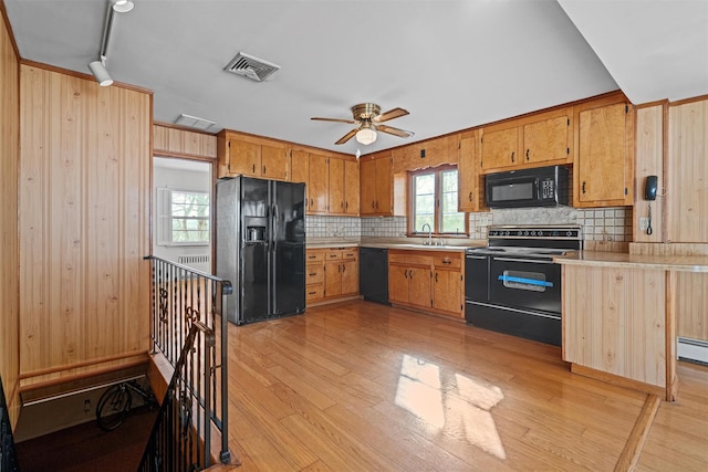 kitchen with visible vents, light countertops, light wood-type flooring, backsplash, and black appliances