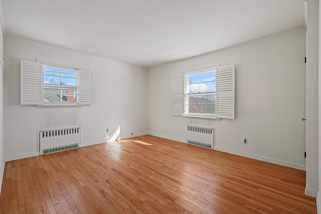 unfurnished room featuring a healthy amount of sunlight, light wood-style floors, and radiator