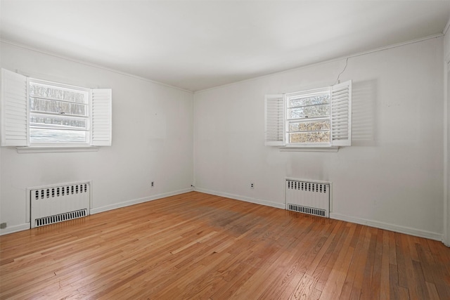 spare room with light wood finished floors, radiator heating unit, and baseboards