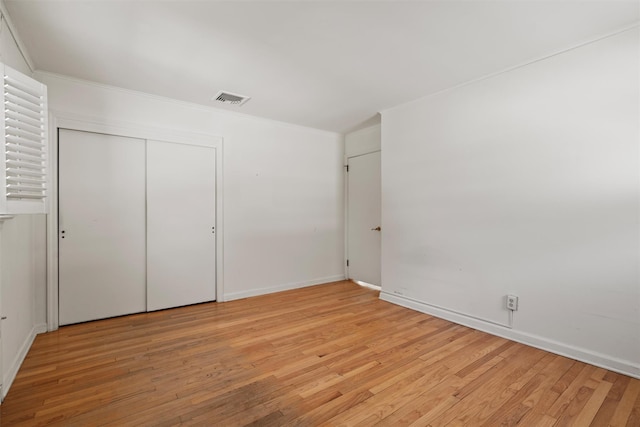 unfurnished bedroom featuring ornamental molding, visible vents, and light wood finished floors