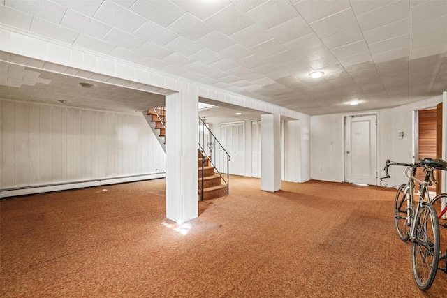 finished basement with a baseboard radiator, stairway, and carpet flooring