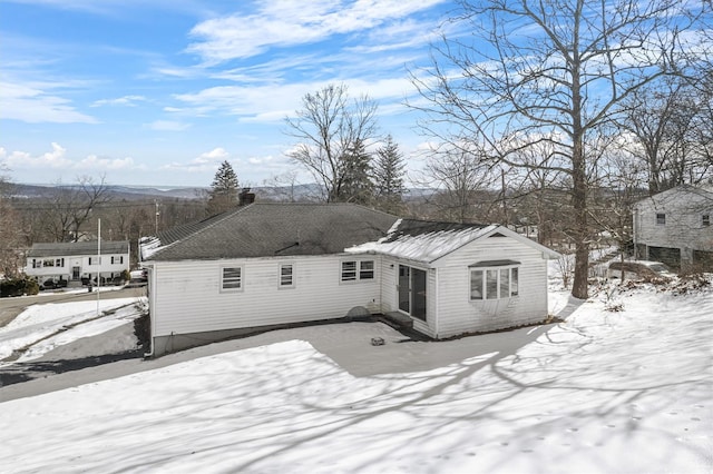 snow covered back of property with a chimney