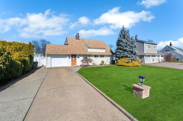 view of front facade with a chimney, concrete driveway, an attached garage, a front yard, and fence