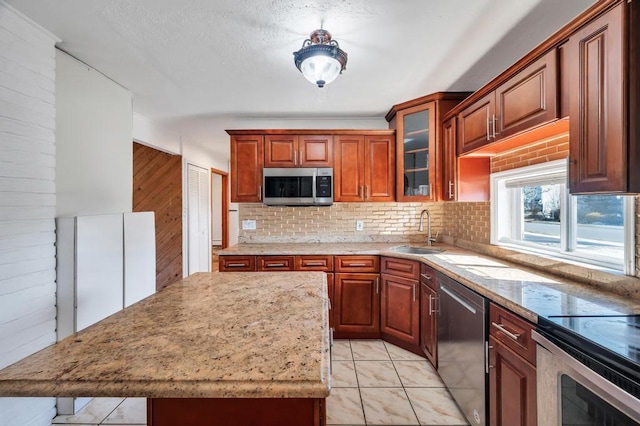 kitchen with stainless steel appliances, tasteful backsplash, glass insert cabinets, a sink, and a kitchen island