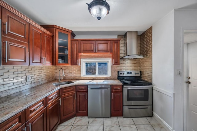 kitchen featuring stainless steel appliances, backsplash, glass insert cabinets, a sink, and wall chimney exhaust hood