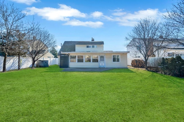 back of house featuring a fenced backyard, a chimney, and a yard