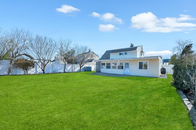 back of property featuring a fenced backyard, a chimney, and a lawn