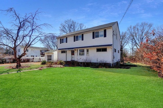 colonial home featuring a front yard and fence