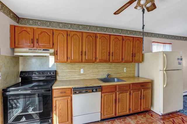 kitchen with white appliances, under cabinet range hood, light countertops, and a sink