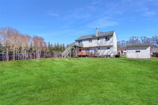 rear view of property with a yard, stairway, a wooden deck, and fence