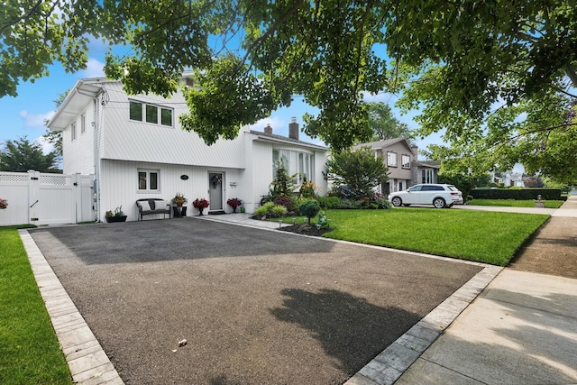 split level home with driveway, a gate, fence, and a front yard