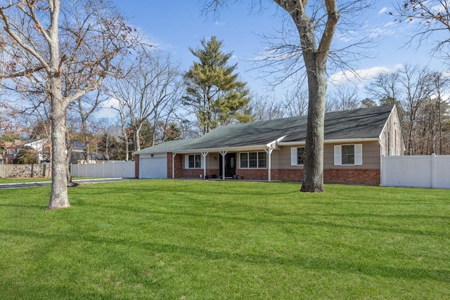 view of front facade featuring a garage, a front yard, brick siding, and fence