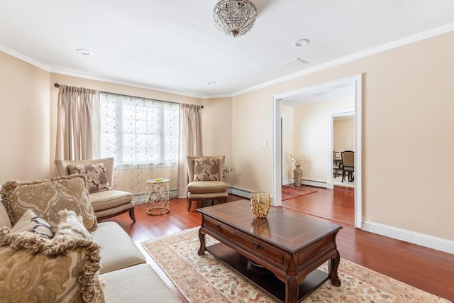 living area with a baseboard heating unit, baseboards, ornamental molding, and wood finished floors