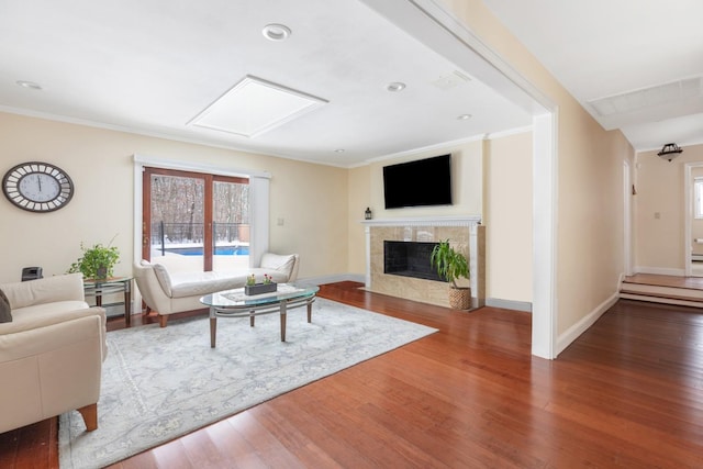 living area with baseboards, ornamental molding, wood finished floors, and a tile fireplace