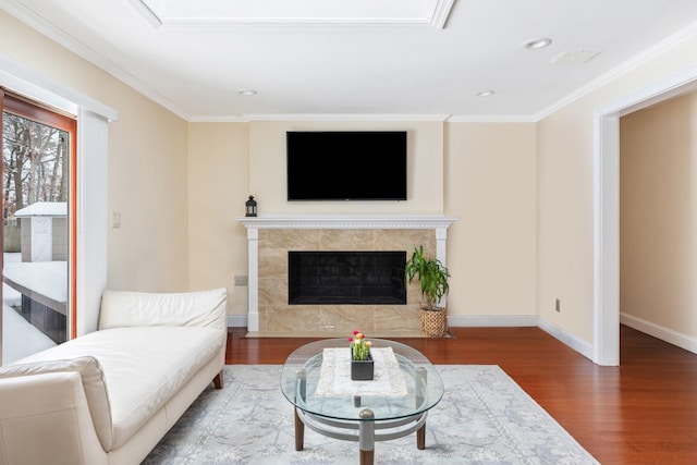 living area featuring baseboards, ornamental molding, a tiled fireplace, and wood finished floors