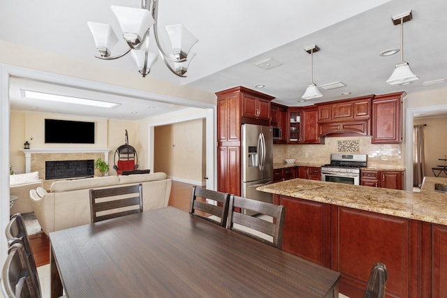 kitchen with reddish brown cabinets, tasteful backsplash, glass insert cabinets, stainless steel appliances, and premium range hood