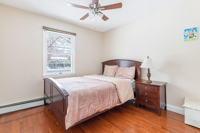 bedroom with baseboards, a baseboard heating unit, ceiling fan, and wood finished floors