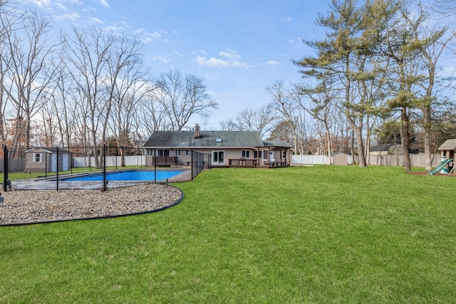 rear view of property with playground community, a lawn, a fenced backyard, and a fenced in pool