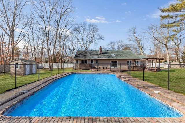 view of pool featuring a wooden deck, a fenced in pool, a lawn, fence, and an outdoor structure