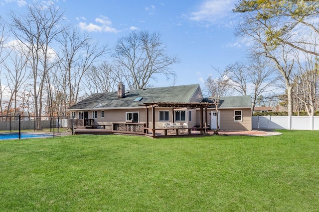 back of house with a deck, a fenced backyard, a lawn, a fenced in pool, and a chimney