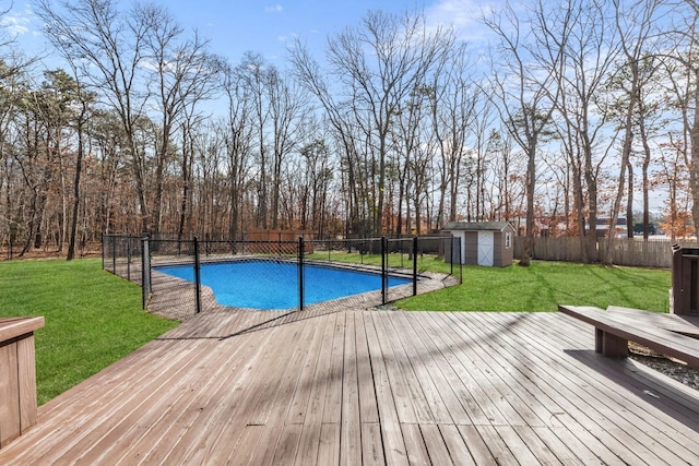 view of pool featuring an outbuilding, a fenced backyard, a storage shed, a wooden deck, and a fenced in pool