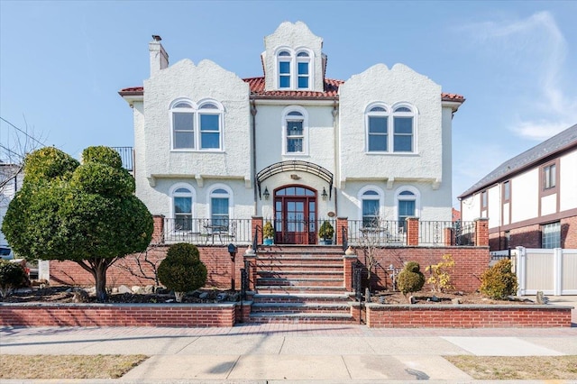 view of front facade featuring french doors, stucco siding, covered porch, fence, and stairs