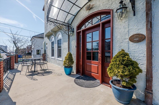 entrance to property featuring stucco siding and outdoor dining space