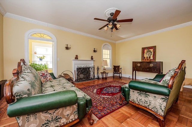 living area with baseboards, a ceiling fan, a fireplace with raised hearth, and crown molding