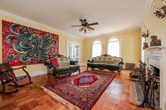 living area featuring a ceiling fan, a fireplace, baseboards, and crown molding