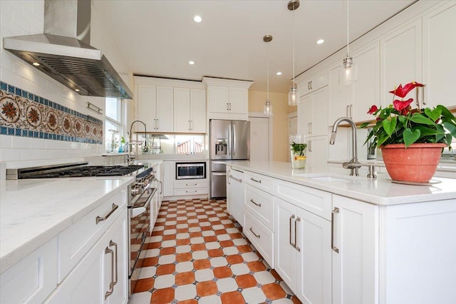 kitchen featuring decorative backsplash, wall chimney exhaust hood, appliances with stainless steel finishes, white cabinetry, and a sink