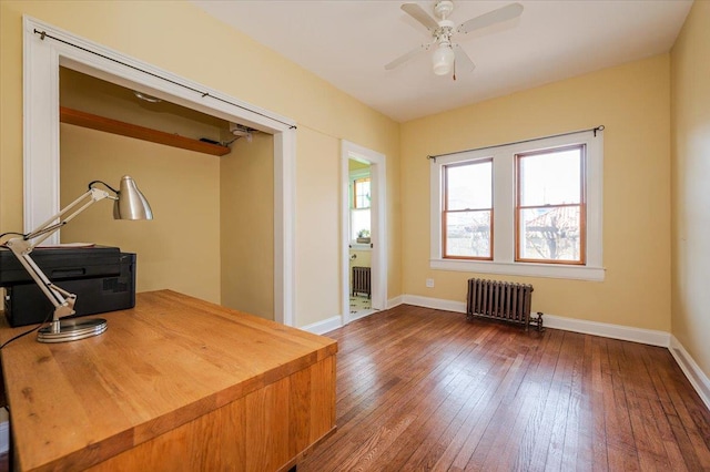 home office featuring radiator, ceiling fan, wood-type flooring, and baseboards