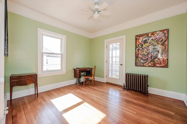 sitting room featuring baseboards, light wood-style flooring, and radiator heating unit