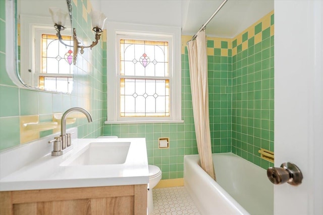 bathroom with toilet, tile patterned floors, shower / bath combo with shower curtain, vanity, and tile walls