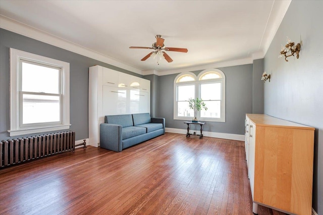 unfurnished living room featuring radiator, baseboards, crown molding, and hardwood / wood-style floors