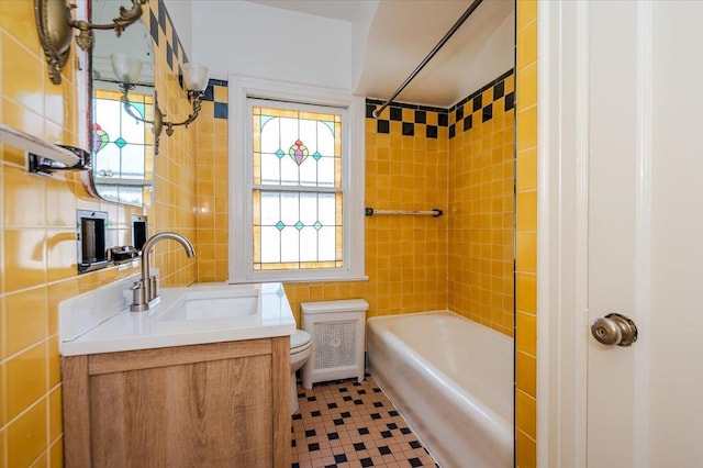 bathroom featuring toilet, bathing tub / shower combination, vanity, tile walls, and radiator heating unit