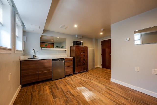 kitchen featuring visible vents, wood finished floors, light countertops, stainless steel dishwasher, and a sink