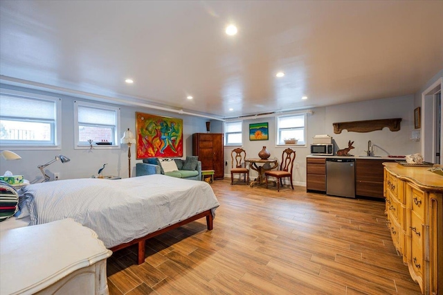 bedroom with light wood-style floors, recessed lighting, and a sink