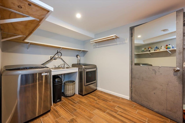 washroom featuring washing machine and dryer, laundry area, a sink, and wood tiled floor