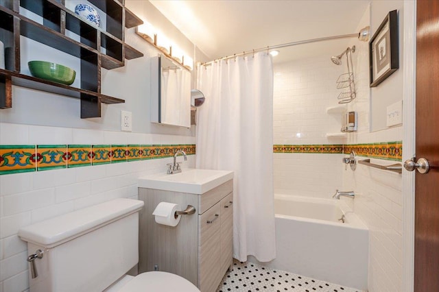 bathroom featuring toilet, vanity, tile walls, wainscoting, and shower / bathtub combination with curtain