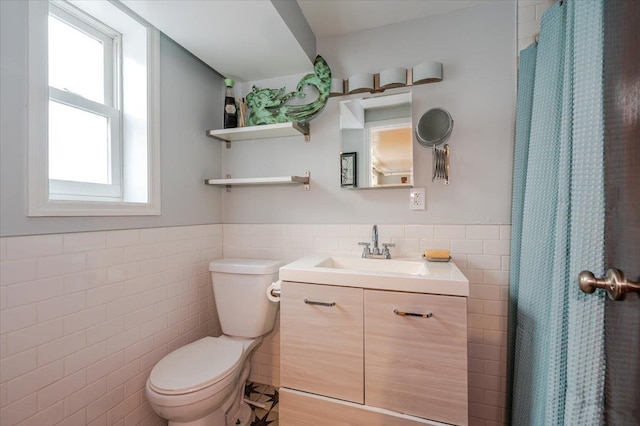 full bathroom with toilet, a wainscoted wall, tile walls, and vanity