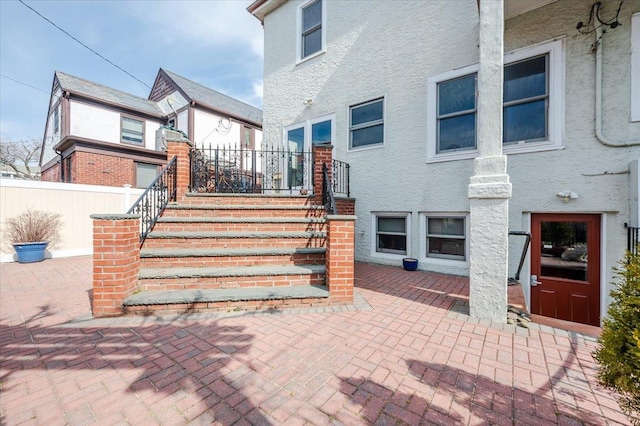 exterior space with fence, a patio, and stucco siding