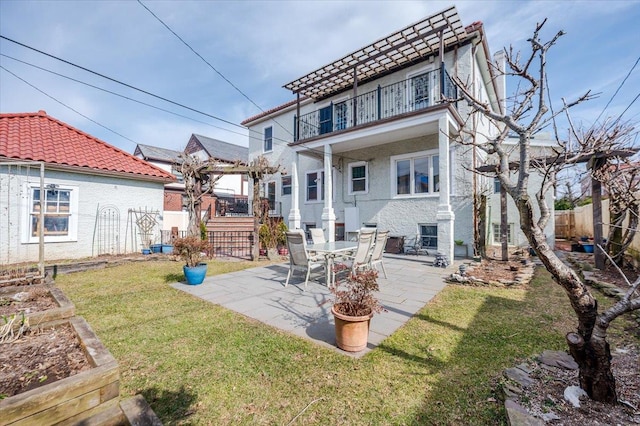 rear view of property featuring a fenced backyard, a balcony, a tiled roof, a lawn, and a patio area