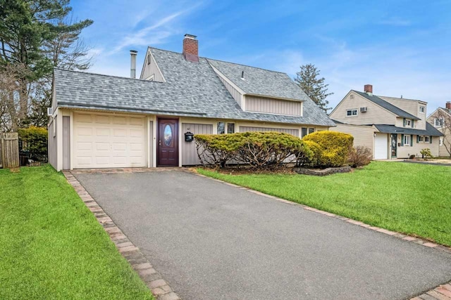 view of front of property with aphalt driveway, an attached garage, a shingled roof, a chimney, and a front yard