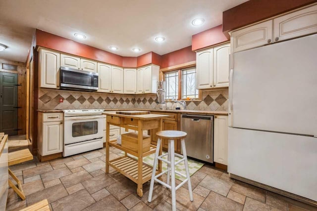 kitchen featuring tasteful backsplash, stainless steel appliances, stone tile flooring, white cabinetry, and recessed lighting