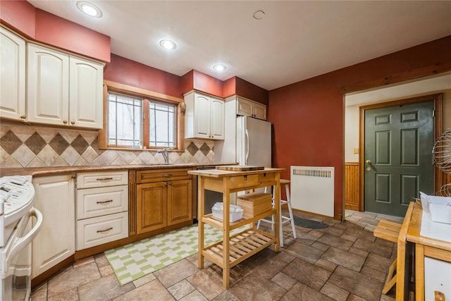 kitchen with freestanding refrigerator, range, radiator heating unit, and stone tile floors