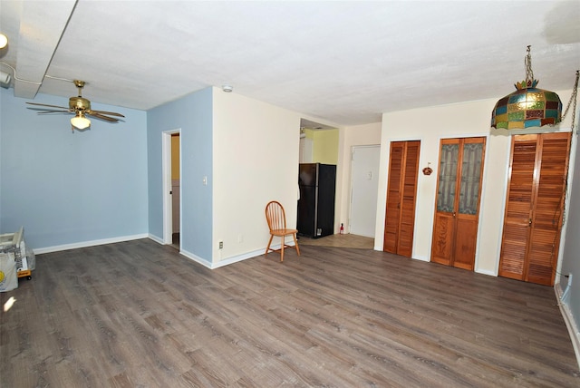 unfurnished living room featuring a ceiling fan, baseboards, and wood finished floors