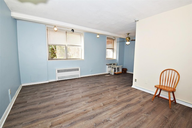 spare room featuring radiator heating unit, baseboards, ceiling fan, and wood finished floors