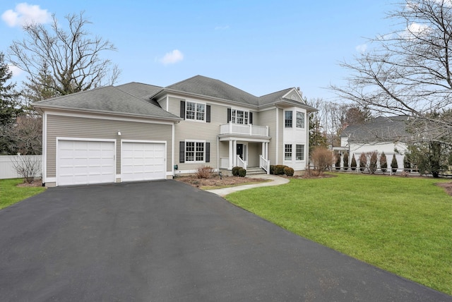 view of front facade featuring driveway, a garage, a balcony, fence, and a front lawn