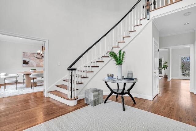 staircase featuring a high ceiling, baseboards, a chandelier, and wood finished floors